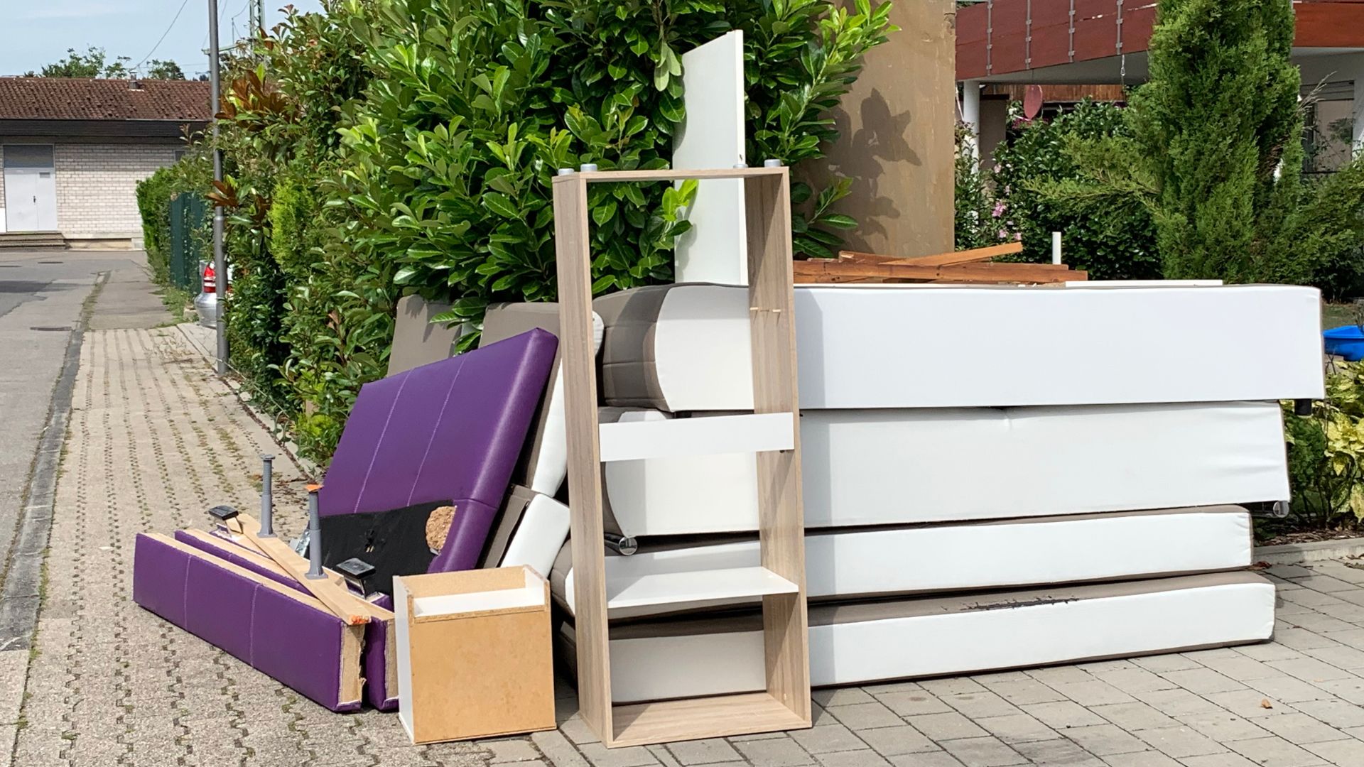 Purple chair, white storage units, and wooden shelving outdoors on sidewalk