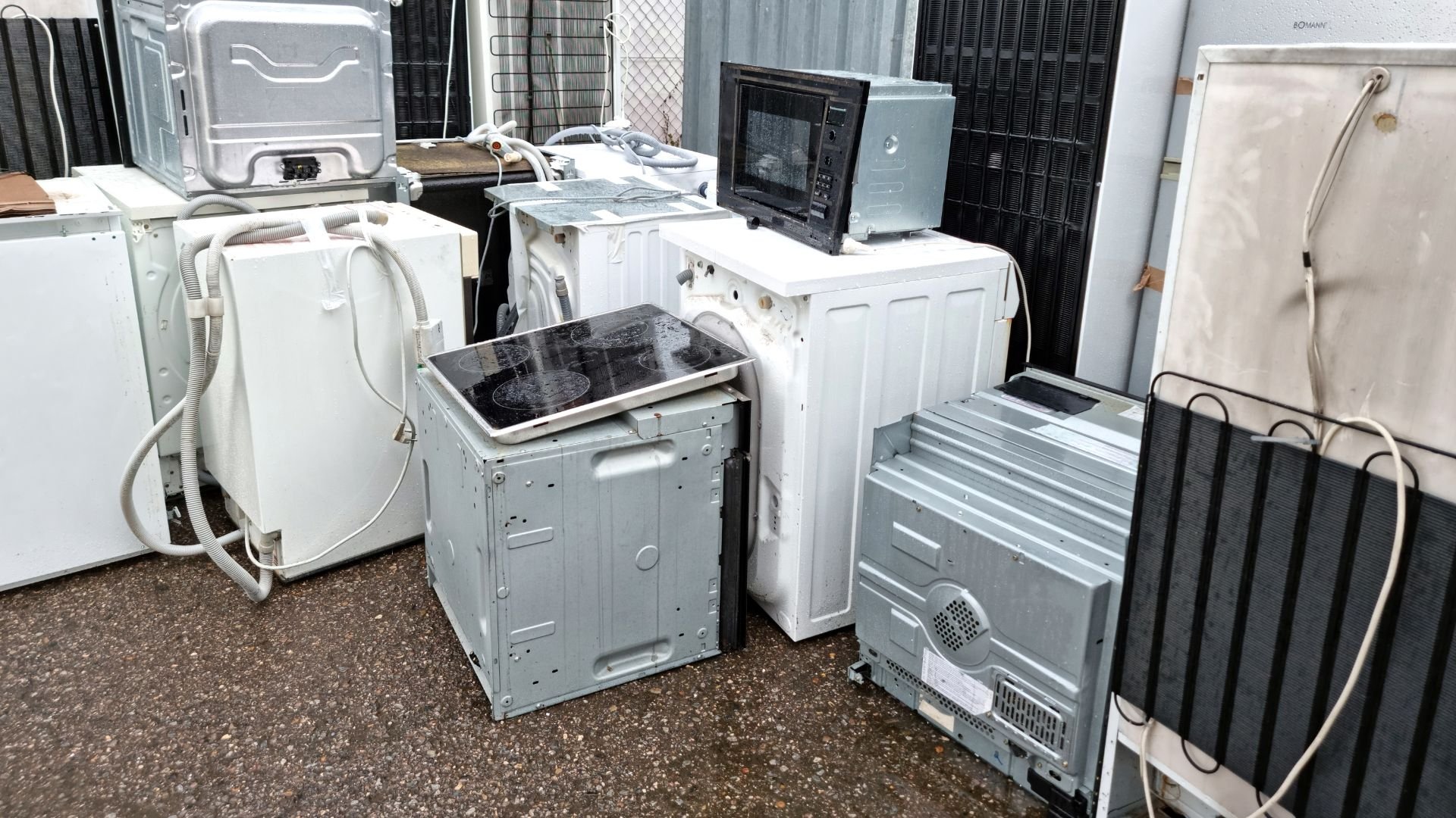 Pile of discarded white appliances and electronic devices in storage area